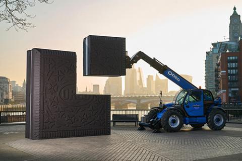 Image of a vehicle lifting part of a giant square-shaped chocolate oreo cookie construction in London