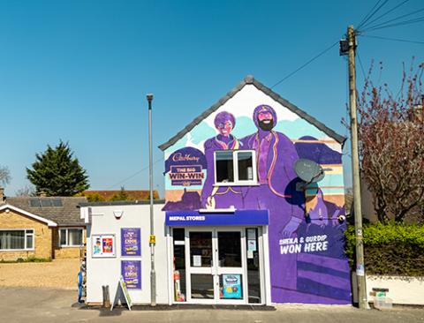 An image of a convenience store with two people in purple painted on the front that are smiling