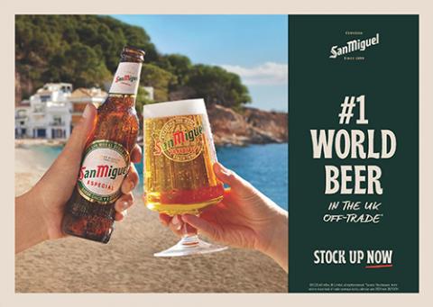 An image of two hands clinking a bottle of beer and a pint of beer together on a beach