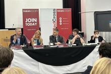 Four people sat behind a table for a panel session in front of an audience